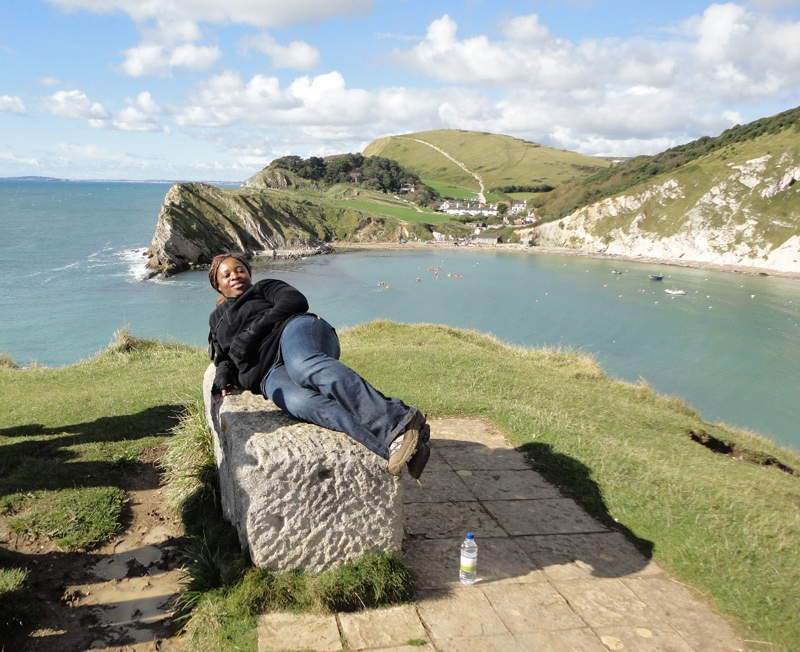 Clara at the Lulworth Cove, Dorset, England. The image is taken from the main path to the cove. The chalk is on the right, the Portland and Purbeck group in the middle, and the Wealden beds to the left.
